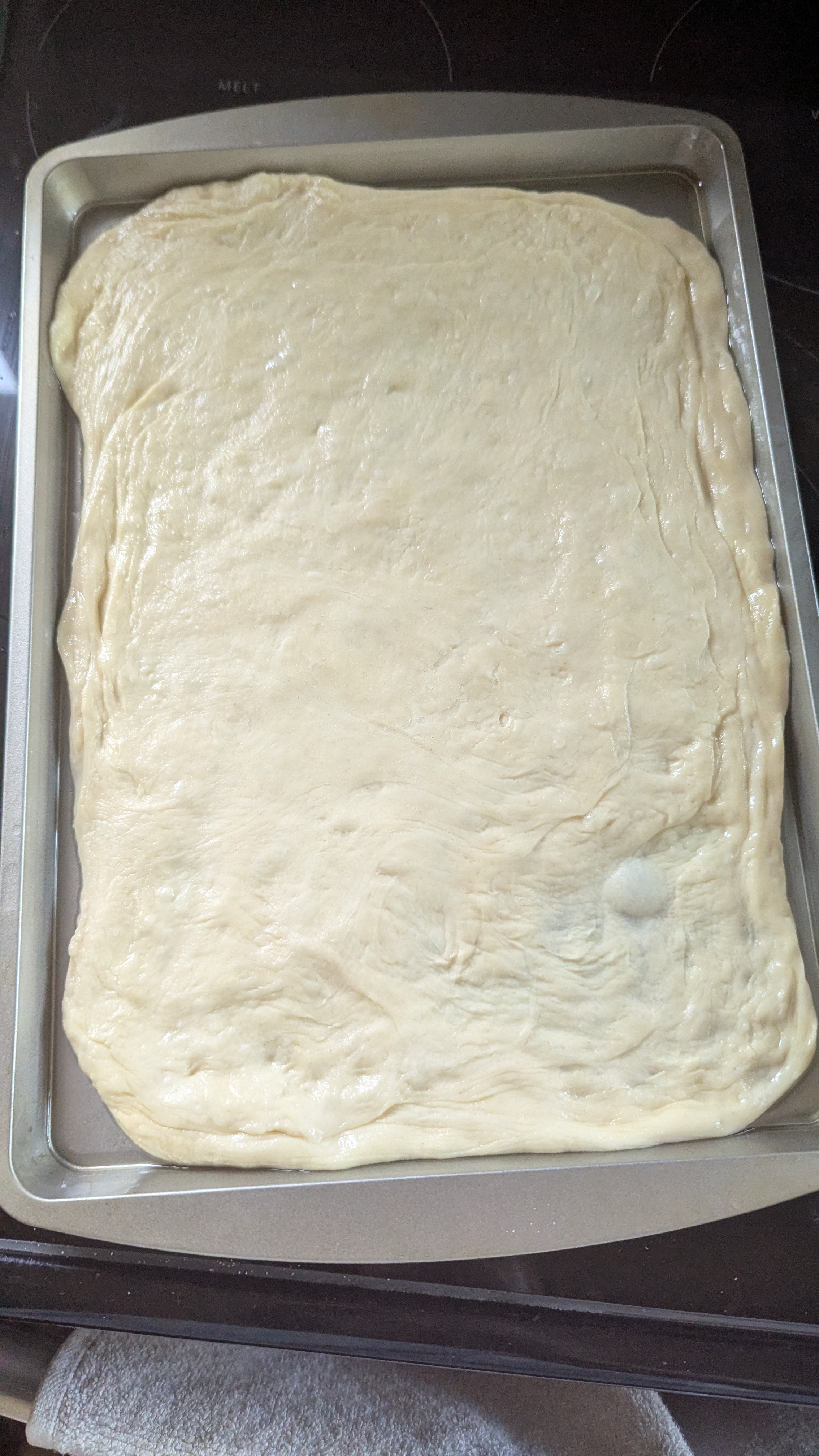 One of the pizza doughs on a cookie sheet